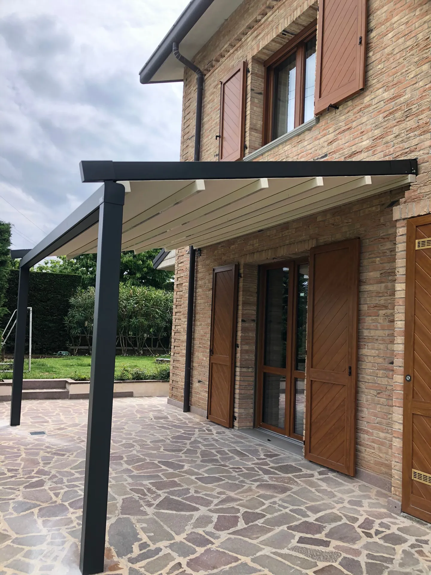 Pergola TendaBerg addossata a una casa in mattoni