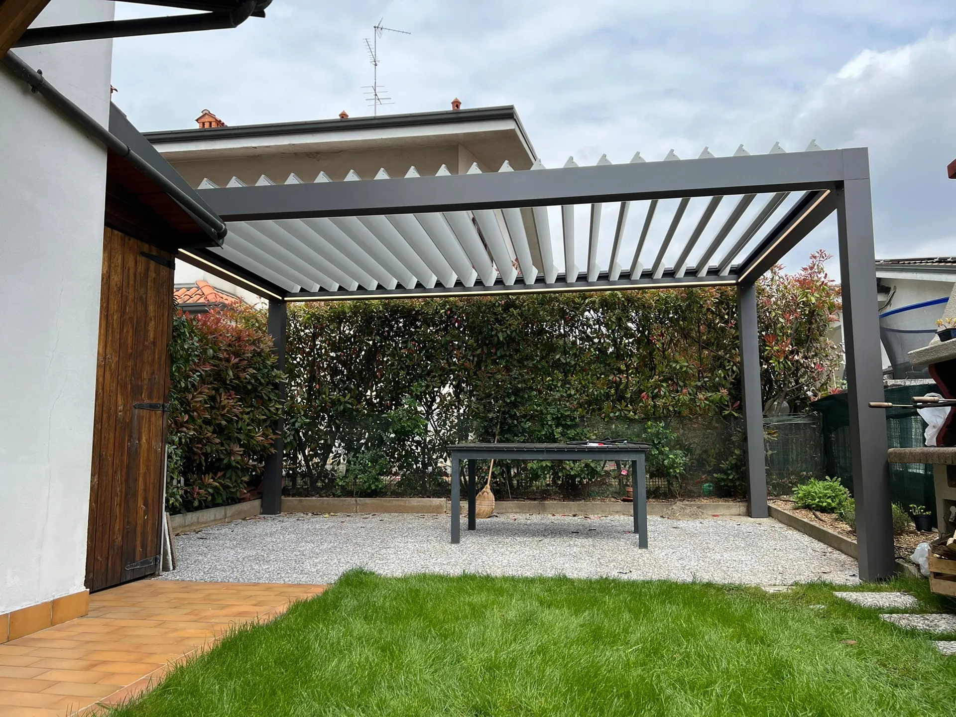 Pergola bioclimatica TendaBerg su un giardino con prato